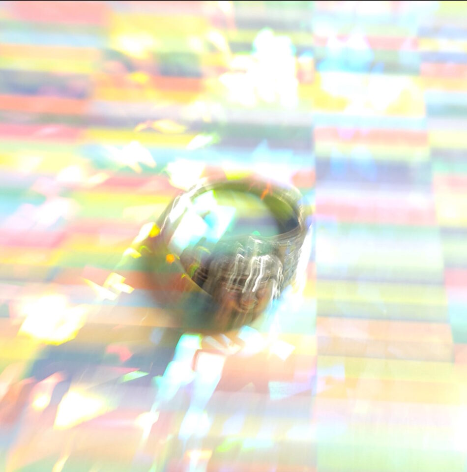 A scattered-light photograph of a silver ring on a rainbow-colored background.